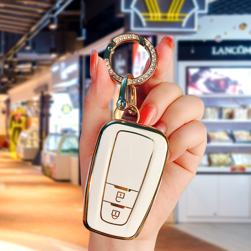Key fob cover for Toyota 2-button keys – TPU – white and gold cover held with crystal keyring close-up