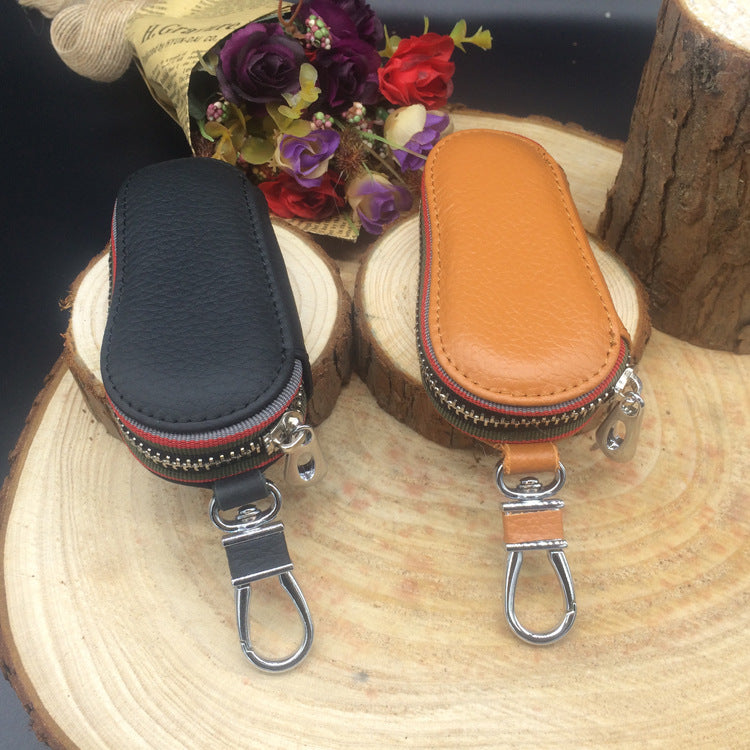 Leather zip car key case – universal – black and tan cases displayed on a log slice