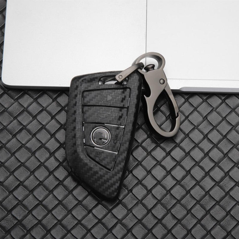 Replacement 4-button smart key case for BMW – carbon fibre case with keyring at an angle on woven leather