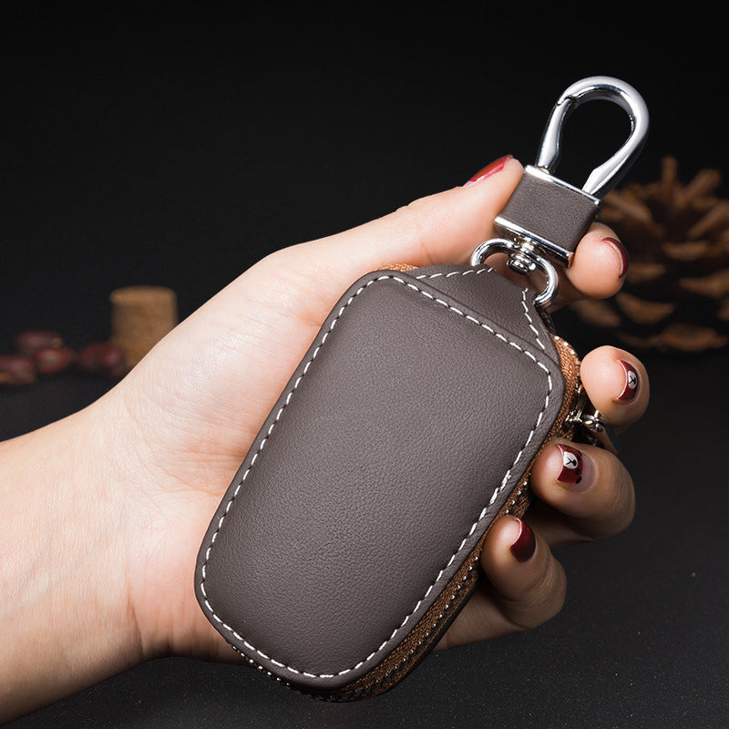 Cowhide leather zip cover for smart car keys – brown pouch held in a hand showing stitching detail