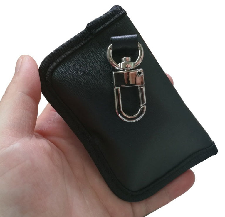 Black PU car key case with anti-scan protection – held in hand showing clip and rear side