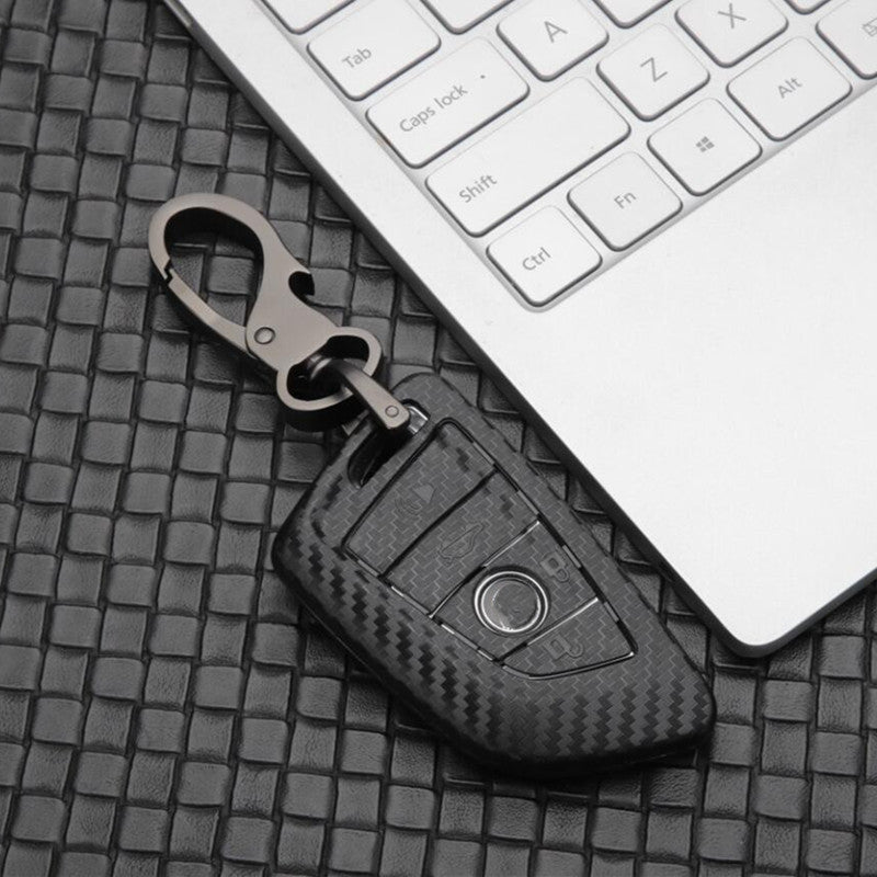 Replacement 4-button smart key case for BMW – carbon fibre case with keyring beside a keyboard